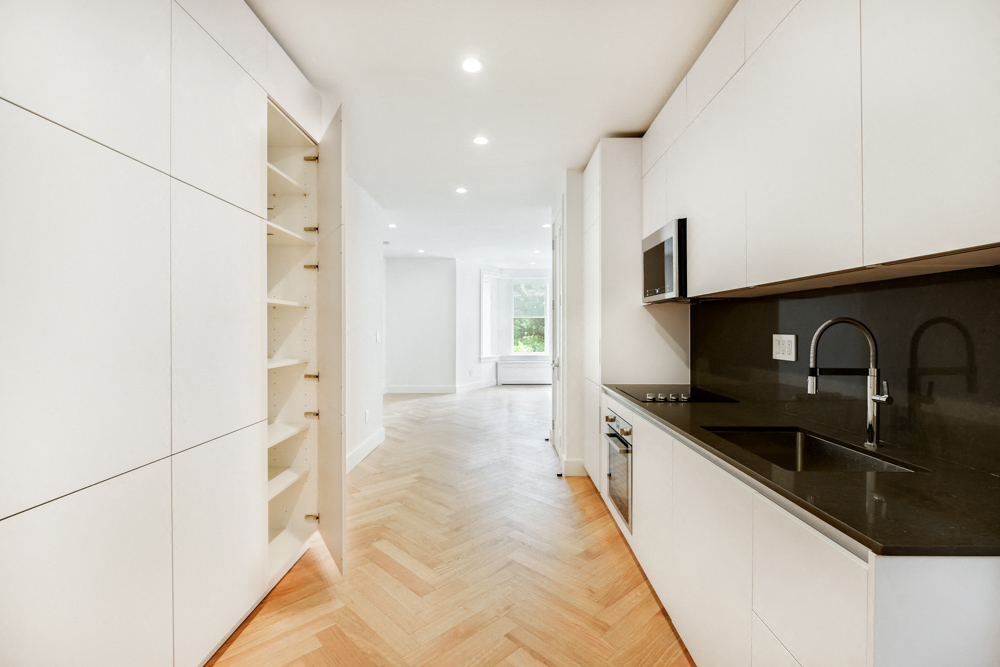 A modern kitchen with white cabinets and a black countertop.